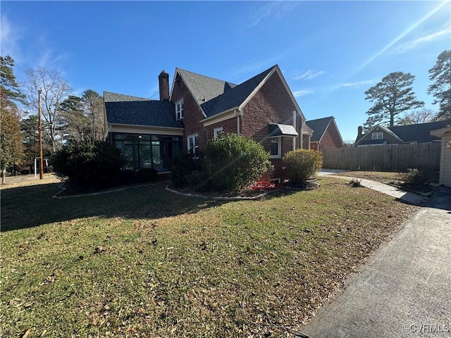 view of side of property with a sunroom and a lawn