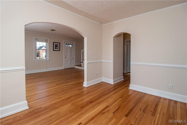 spare room with light hardwood / wood-style flooring, a textured ceiling, and ornamental molding