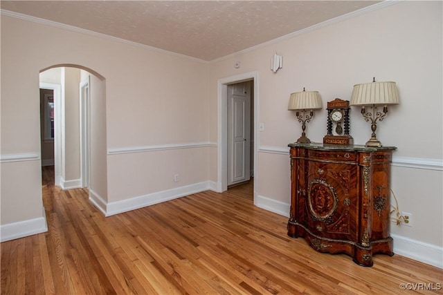 unfurnished room featuring ornamental molding, a textured ceiling, and light hardwood / wood-style flooring