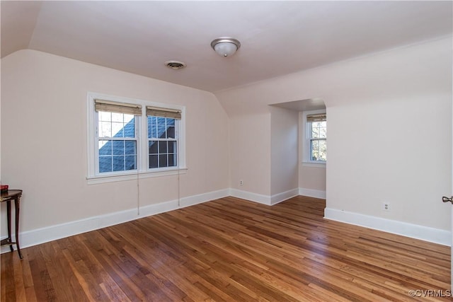 additional living space with plenty of natural light, wood-type flooring, and vaulted ceiling