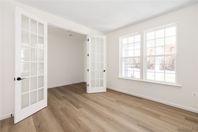 unfurnished bedroom with wood finished floors, french doors, and baseboards