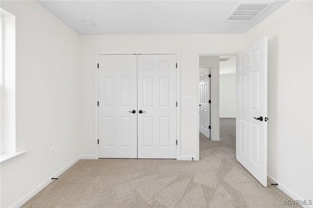 unfurnished bedroom with light colored carpet and a closet