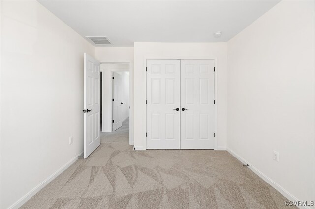 unfurnished bedroom with a closet and light colored carpet