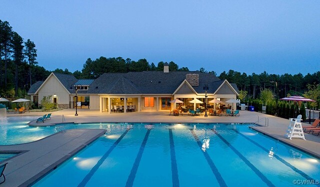 pool at dusk featuring a patio area