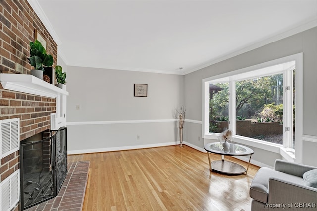 living area featuring a fireplace, hardwood / wood-style flooring, and crown molding