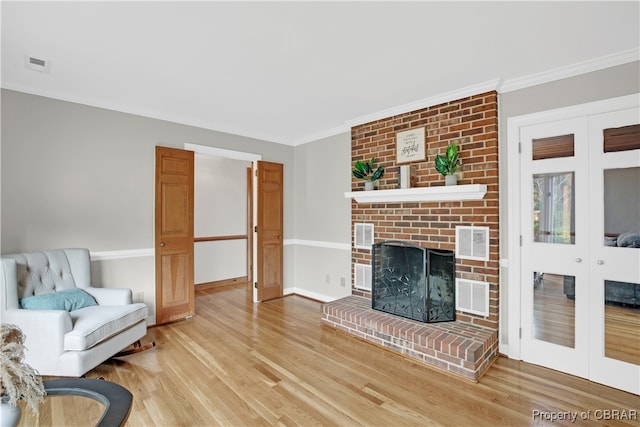 living room with a fireplace, wood-type flooring, french doors, and ornamental molding