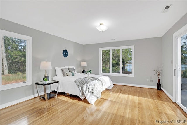 bedroom with hardwood / wood-style floors, access to outside, and multiple windows