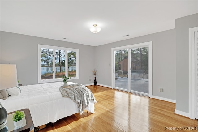 bedroom featuring hardwood / wood-style floors, access to outside, and multiple windows