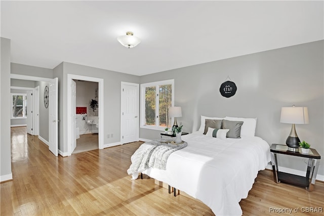 bedroom featuring ensuite bath and hardwood / wood-style floors