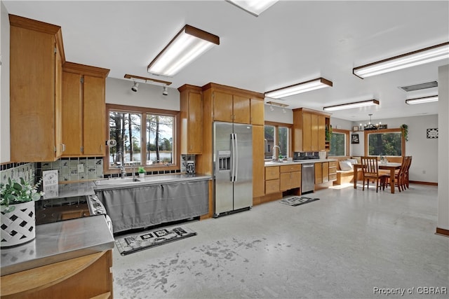 kitchen with appliances with stainless steel finishes, backsplash, hanging light fixtures, and sink