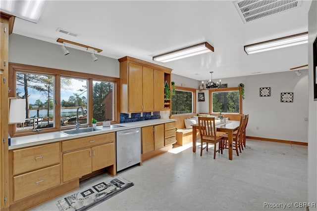 kitchen featuring stainless steel dishwasher, a healthy amount of sunlight, sink, and an inviting chandelier