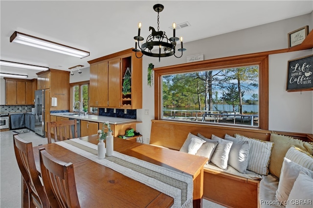 dining area with a wealth of natural light, sink, and a notable chandelier