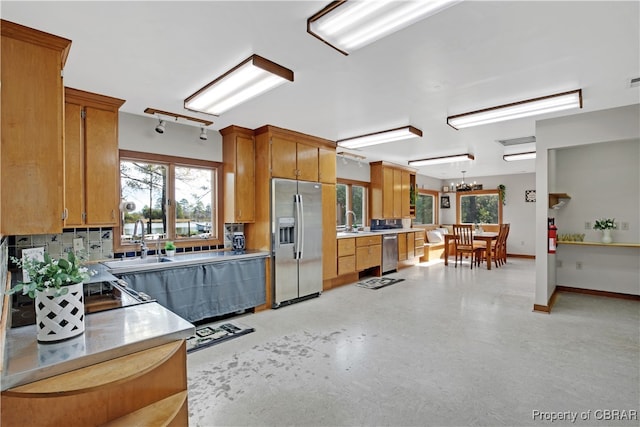 kitchen with backsplash, hanging light fixtures, stainless steel appliances, and sink