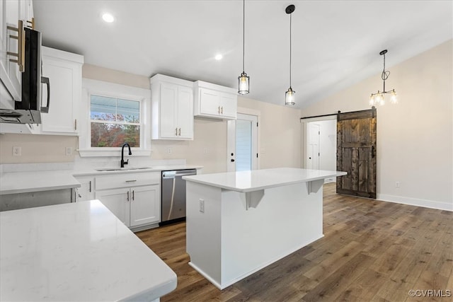 kitchen with white cabinets, sink, a barn door, appliances with stainless steel finishes, and a kitchen island