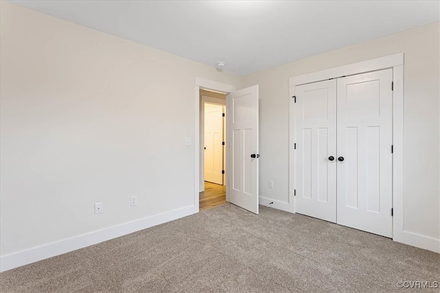 unfurnished bedroom with light colored carpet and a closet