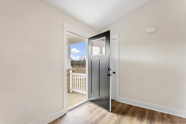 doorway with hardwood / wood-style flooring and vaulted ceiling