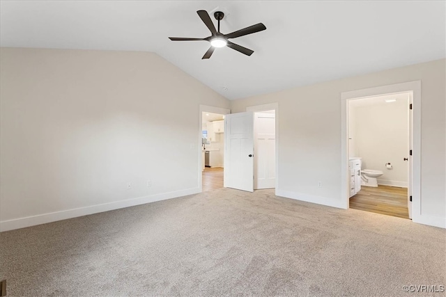 unfurnished bedroom featuring connected bathroom, ceiling fan, vaulted ceiling, a walk in closet, and a closet