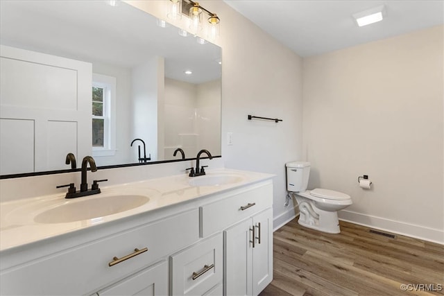 bathroom with a shower, hardwood / wood-style floors, vanity, and toilet