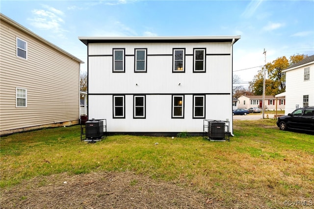 rear view of property with a lawn and cooling unit