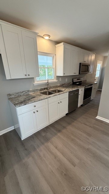 kitchen with white cabinetry, sink, stainless steel appliances, stone countertops, and hardwood / wood-style flooring