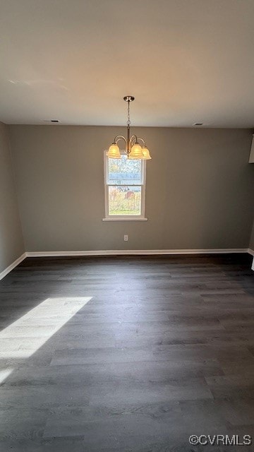 empty room featuring a chandelier and dark wood-type flooring