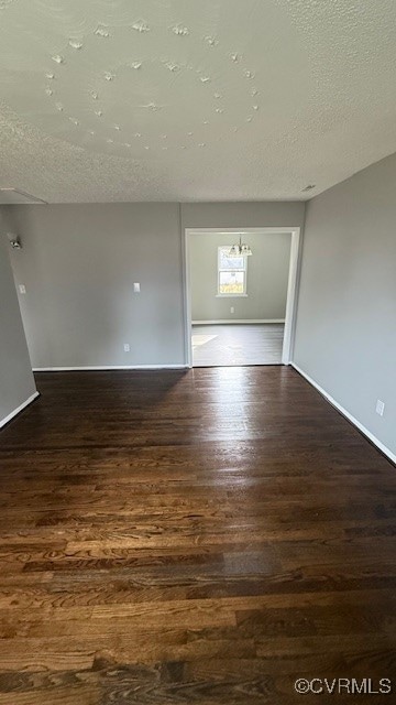 spare room featuring a textured ceiling and dark wood-type flooring