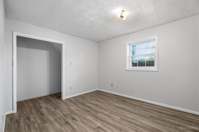 unfurnished room with a textured ceiling and dark hardwood / wood-style flooring