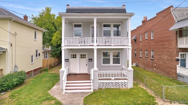 view of front of house featuring covered porch, brick siding, fence, and a balcony