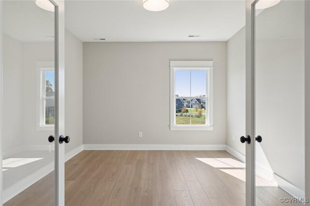 empty room featuring french doors and light wood-type flooring