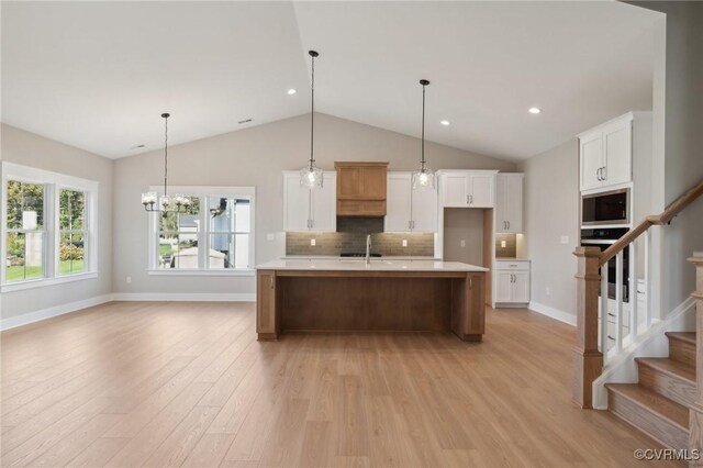 kitchen featuring white cabinetry, a center island with sink, decorative light fixtures, and appliances with stainless steel finishes