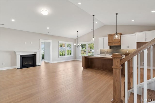 TBD2 Rocky Ford Rd, Beaverdam, VA 23015 - kitchen featuring light wood finished floors, lofted ceiling, a fireplace with flush hearth, a kitchen breakfast bar, and tasteful backsplash