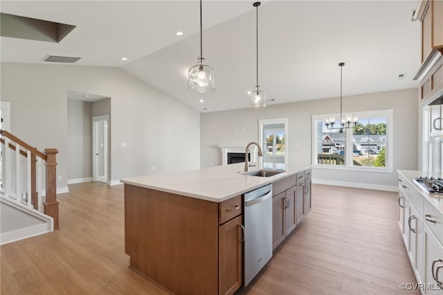 kitchen featuring stainless steel appliances, sink, decorative light fixtures, light hardwood / wood-style floors, and lofted ceiling