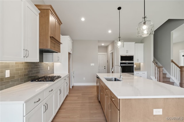 kitchen featuring appliances with stainless steel finishes, a spacious island, sink, pendant lighting, and white cabinets