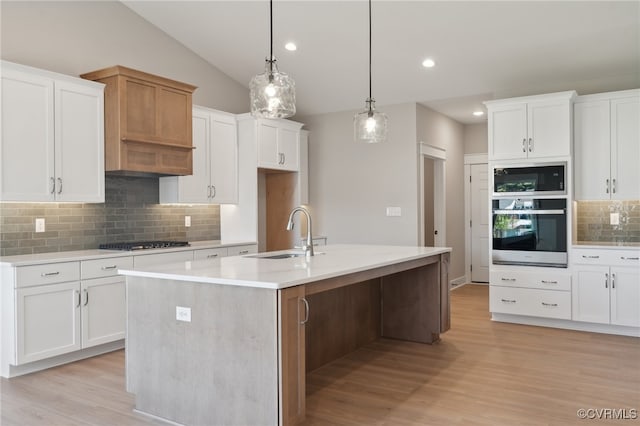 kitchen with gas cooktop, a kitchen island with sink, sink, light hardwood / wood-style flooring, and white cabinets