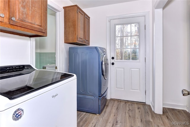 laundry area featuring cabinets, washing machine and clothes dryer, and light hardwood / wood-style floors