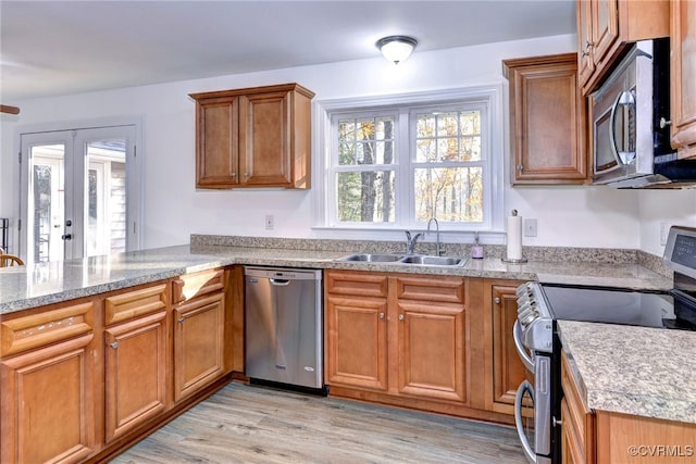 kitchen with sink, kitchen peninsula, stainless steel appliances, light wood-type flooring, and french doors