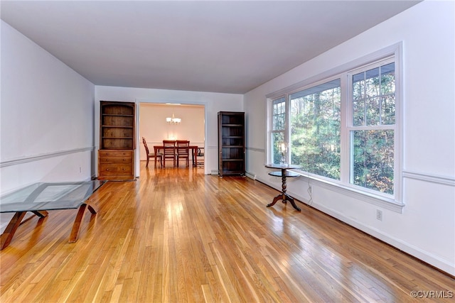 spare room with plenty of natural light, a chandelier, and light wood-type flooring