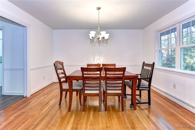 dining space featuring a baseboard heating unit, light wood-type flooring, and a notable chandelier