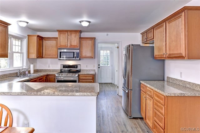 kitchen featuring appliances with stainless steel finishes, light hardwood / wood-style floors, sink, and kitchen peninsula