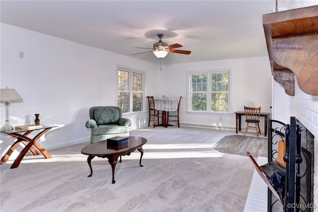 sitting room featuring a tiled fireplace, light colored carpet, and ceiling fan