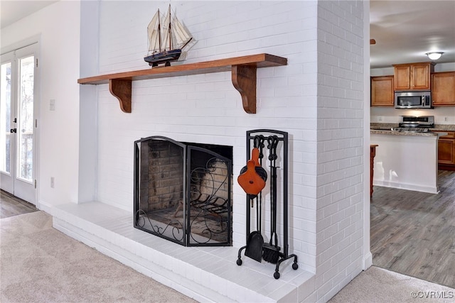 room details with stainless steel appliances, a brick fireplace, and carpet floors