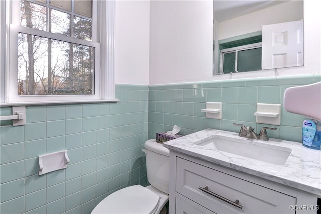 bathroom with vanity, toilet, and tile walls