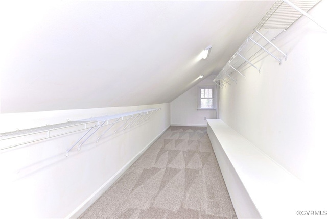 spacious closet with light colored carpet and vaulted ceiling