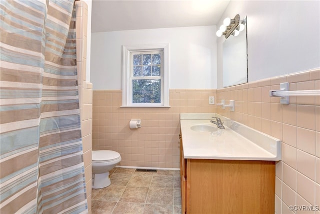 bathroom with vanity, tile walls, and toilet