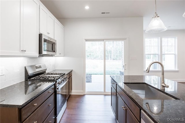 kitchen with white cabinetry, sink, stainless steel appliances, and dark stone counters