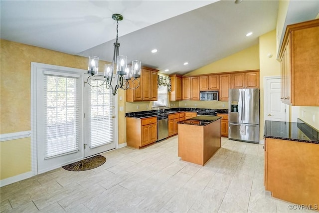 kitchen featuring stainless steel appliances, dark stone counters, pendant lighting, vaulted ceiling, and a kitchen island