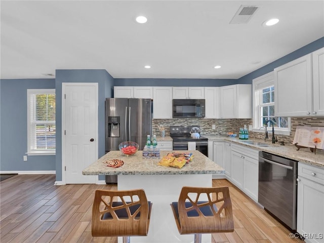 kitchen featuring a center island, appliances with stainless steel finishes, sink, and a breakfast bar