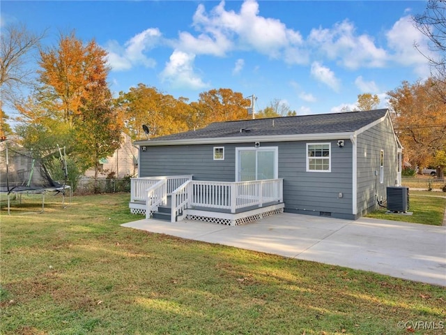 rear view of property with a patio, a wooden deck, a trampoline, a yard, and central AC