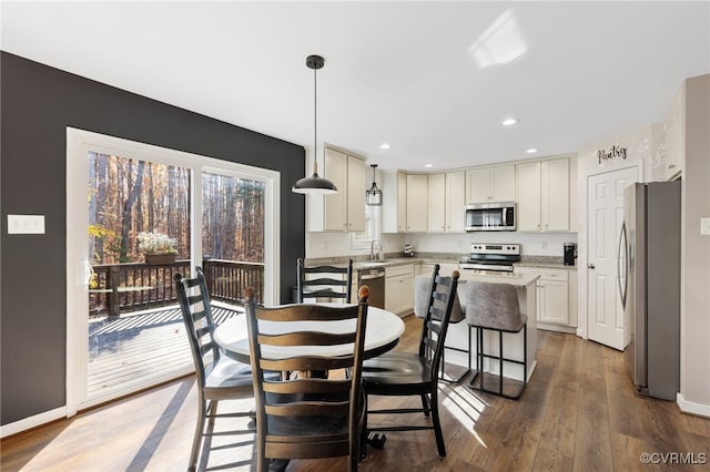 interior space with a breakfast bar, a center island, hanging light fixtures, dark hardwood / wood-style floors, and appliances with stainless steel finishes