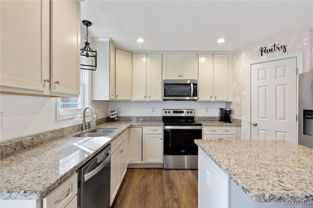 kitchen with sink, dark wood-type flooring, light stone counters, decorative light fixtures, and appliances with stainless steel finishes